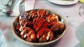 Slow motion capturing crispy spanish patatas bravas croquette lifting from plate, drizzled with vibrant sauce and sprinkled with aromatic spices. Crispy spanish patatas bravas croquette rising by fork video