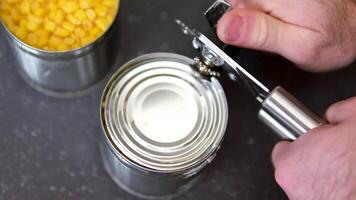 A can opener with a tin can rotates on a grey background. Metal can opener. Close-up. video
