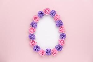 Pastel violet rosebuds egg shape on pink background. Versatile Easter-themed composition perfect for backgrounds, greeting cards, social media, and seasonal marketing. photo