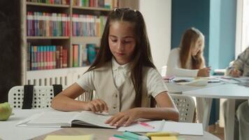 Clever little girl pupil at classroom studying reading book prepare study lesson schoolgirl kid child reader learning textbook library cognition read in school academy smiling teen student education video