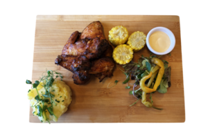 Grilled chicken wings, mashed potatoes, pepper salad and corn and sauce on wooden board, tasty dish of traditional Czech cuisine, isolated object soft selective focus, clipping path png
