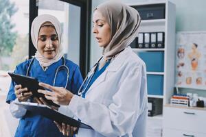 Two women in hijab are looking at a tablet photo