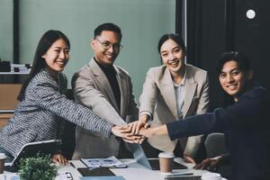 Asian business people holding hands in an office photo