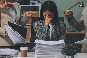 Three business people are sitting at a desk with papers photo