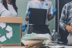 Three people are standing around a table with recycling boxes photo