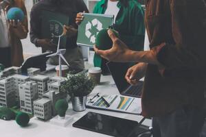 A group of people are standing around a table with a green building photo