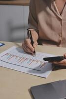 A woman is using a pen and paper to write on a paper with a graph on it photo