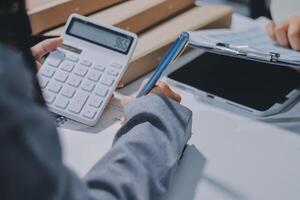 Two people are working on a calculator and a notebook photo