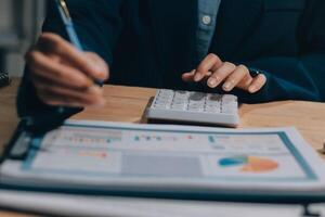 A person in a business suit is using a calculator and pen to write on a paper photo