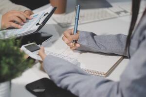 A woman is writing on a notebook while another person is using a calculator photo