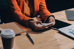 A person is using a smartphone while sitting at a desk photo