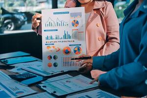 Two business people standing in front of a table with graphs and papers photo