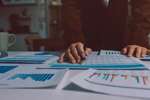 A person in a suit is working on a table with papers and graphs photo