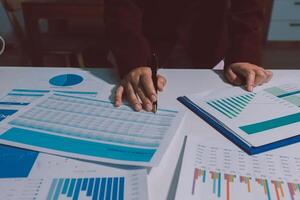 A business person is working on a spreadsheet with graphs and papers photo