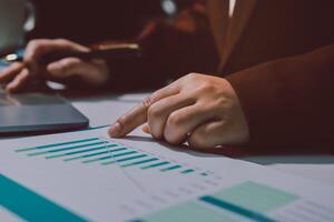 A person in a suit is using a laptop and pointing at a chart photo