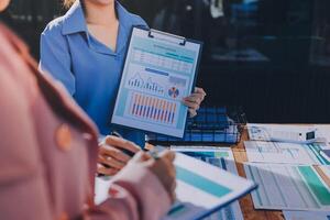 Two business people standing in front of a table with papers and graphs photo