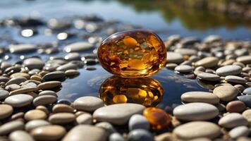 A polished amber stone resting on smooth pebbles by a reflective water surface in a natural setting. photo