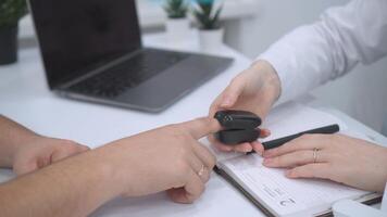 A close-up of a doctors hand placing a pulse oximeter on a patient finger. The medical device is monitoring the patient pulse and oxygen levels. The patients hand rests calmly on a white surface video