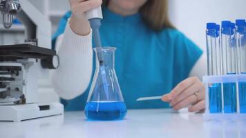 Closeup of a scientists hands wearing blue gloves, carefully holding a transparent microscope slide. The image focuses on the precision and attention to detail required in laboratory work, with a video