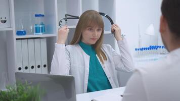 Close-up of a female doctor holding and adjusting a stethoscope while seated. The image highlights medical tools and professionalism in a healthcare environment. video