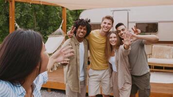 Multiracial friends gather at a campsite, sharing laughter and bonding. They relax under a shelter, capturing memories in the sunlit summer atmosphere, embodying friendship and joy. video