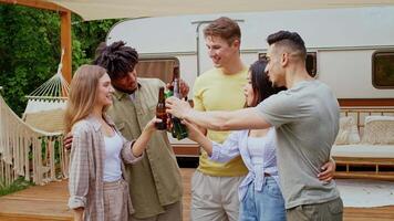 A diverse group of friends gathers to share drinks and laughter at a camping spot. They are enjoying a summer weekend together in a relaxed outdoor setting. video