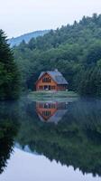 Serene Lakeside Cabin Reflecting in Tranquil Water photo