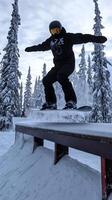 Snowboarder Jumping Over Rail in Snowy Mountain photo