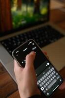 Hands hold a smartphone displaying a ChatGPT conversation, with an open laptop visible in the background. photo