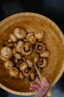 Close-up of marinated mushrooms, baked to perfection, served in a wooden bowl, with a rich, earthy flavor. photo