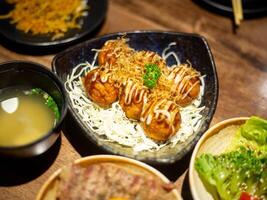 Takoyaki set served with Japanese food, miso soup, and grilled pork on rice. photo