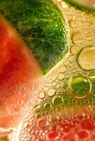 Close up of the watermelon cocktail with bubbles trapped under a lime slice, mint leaves in the icy texture. photo