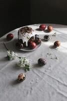 Traditional Ukrainian Easter bread Paska and easter eggs Pysanka in black, red and white colors with cherry blossom on a table. Easter still life. photo