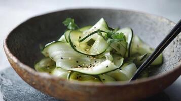 A delicate composition of fresh paper-thin zucchini ribbons in a handmade clay bowl with a raw, unglazed finish. photo