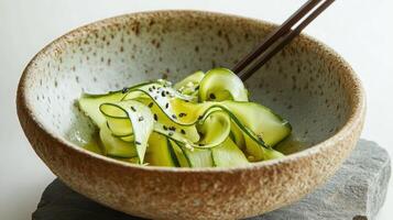 A delicate composition of fresh paper-thin zucchini ribbons with seeds in a handmade clay bowl with a raw, unglazed finish. photo