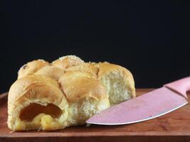 Homemade wheat bread with sesame seeds and cheese. knife, black background photo