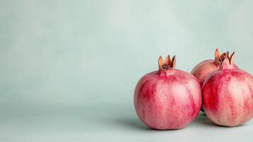 Three fresh pomegranates on light blue background with soft shadows photo