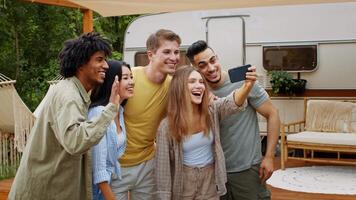 A group of diverse friends smiles and poses for a selfie in an outdoor camping setting during a sunny summer weekend, exploring their friendship and shared adventures. video