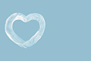 Cream heart shape on blue background with copy space, cream symbol evokes skincare, love and softness. Cream expresses gentle care, cream design ideal for wellness, beauty or Valentine's visuals photo