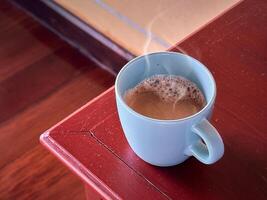 Closeup cup of coffee on the corner of wood table photo