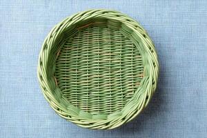 Woven green basket placed on a textured blue surface showcasing craftsmanship and design suitability for various uses photo