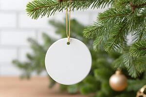 Blank circular ornament for mockup hanging from a Christmas tree branch with festive decor in the background and soft lighting photo