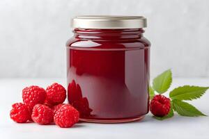 Raspberry jam in a glass jar for mockup with fresh raspberries and green leaves displayed against a light background, perfect for showcasing homemade preserves photo