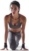 Athletic female runner in starting pose, showcasing determination and focus. She wears gray sports outfit, emphasizing her athletic build and readiness for action photo