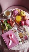 creative flat lay featuring pink themed breakfast spread with fruits, vegetables, and book, symbolizing cancer awareness. scene evokes sense of health and positivity photo