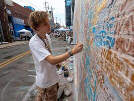 young artist is painting vibrant mural on brick wall, showcasing creativity and expression in urban setting. scene captures essence of community art and youthful energy photo