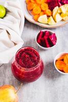 A glass with a mixture of beetroot, apple and carrot juices ABC on the table vertical view photo