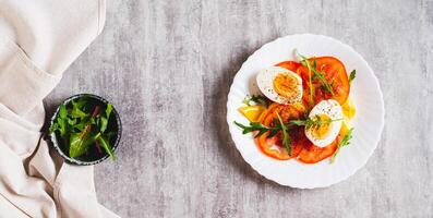 Tomato slices, egg, cheese and herbs on a plate on the table top view web banner photo