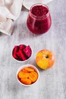 Beetroot, carrot and apple pieces in bowls for making ABC juice on the table vertical view photo