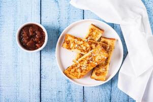Appetizing croutons in powdered sugar on a plate on the table top view photo